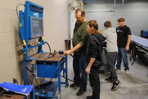 college instructor Paul Ericson showing high school student how to use welding simulator